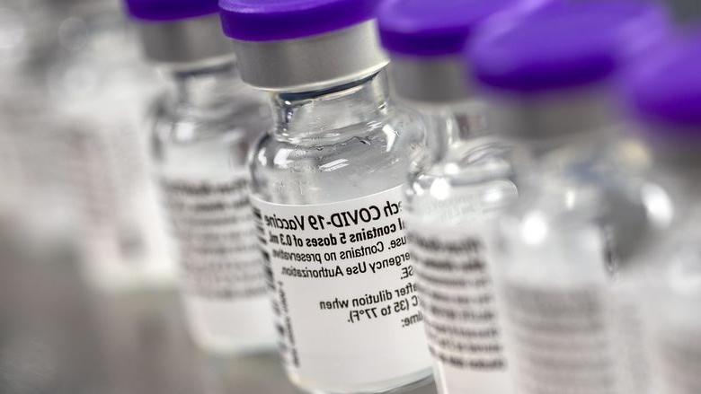 一排小瓶上的标签表明它们含有COVID-19疫苗.